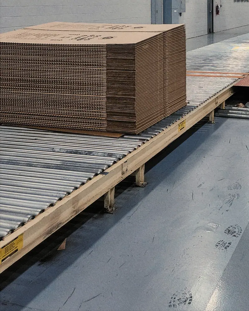Stacks of flat corrugated board on a roller conveyor